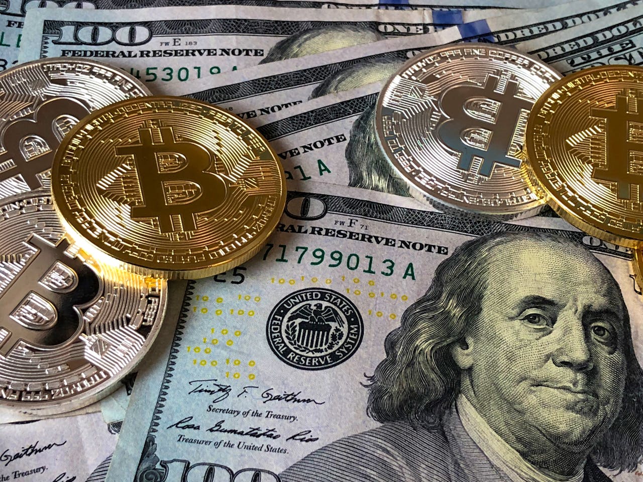 our-story A close-up photo depicting Bitcoin coins on top of US dollar bills, symbolizing finance and cryptocurrency.